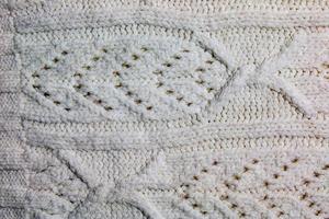 The texture of a large knit sweater or scarf. Knitted background with a relief pattern. Wool hand or machine knitting. Fabric background. photo