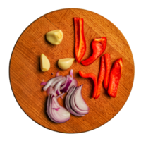 Peeled garlic cloves, chopped fresh red pepper and chopped red onion on a wooden kitchen board png