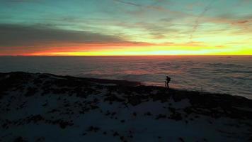 Climber walks on the peak of the mountain at sunset with fog at the valley video