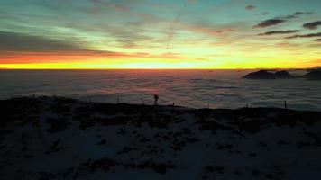 klättrare promenader på de topp av de berg på solnedgång med dimma på de dal video