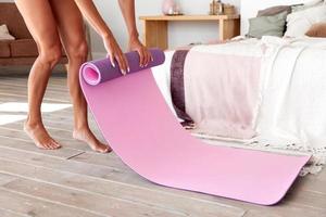 Woman unrolling yoga mat before exercise photo