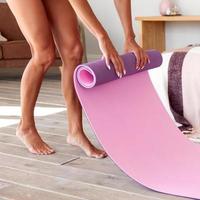 Woman unrolling yoga mat before exercise photo