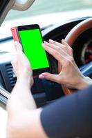 woman driver with a smartphone in her hands while driving photo