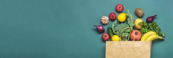 bolsa de papel ecológica con vegetales verdes orgánicos crudos aislados en fondo verde plano, vista superior cero desperdicio, concepto libre de plástico dieta saludable y desintoxicación, concepto de agricultura foto