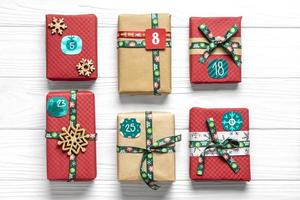 Handmade wrapped red, green gift boxes decorated with ribbons, snowflakes and numbers, Christmas decorations and decor on white table Xmas advent calendar concept Top view Flat lay Holiday card photo