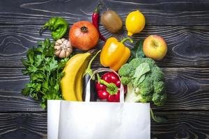 bolsa de papel ecológica con vegetales verdes orgánicos crudos aislados sobre fondo de madera plano, vista superior cero desperdicio, concepto libre de plástico dieta sana y limpia, desintoxicación, concepto de agricultura foto