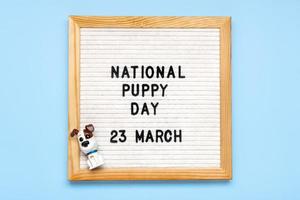 Felt board with text National puppy day in 23 march, cute dog figures on blue background Top view Flat lay Holiday greeting card photo