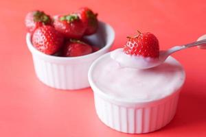Yogurt and strawberry in a bowl on white photo