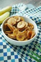 Close up of dried banana chips in a bowl on table . photo