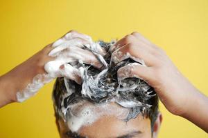 young men washes h his hair with shampoo . photo