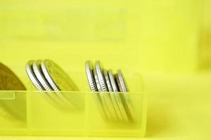 close up of coins in a plastic box on yellow background photo