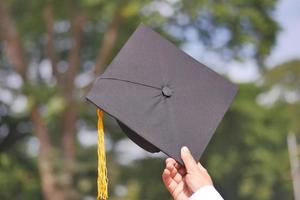 estudiante sostenga sombreros en la mano durante el éxito del comienzo con fondo amarillo foto