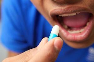 young men putting capsule in his mouth photo