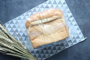 top view of baked bread in a plastic packet on black background photo