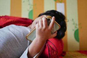 niño usando un teléfono inteligente en la cama foto