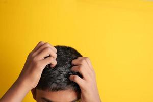 teenage boy Scratching Head Against black background . photo