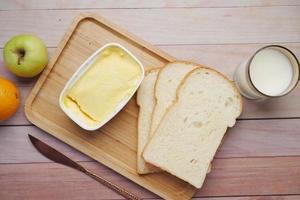 morning breakfast with fresh butter in a container , bread, milk and apple photo