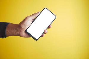 holding a smart phone with white empty screen against yellow background photo