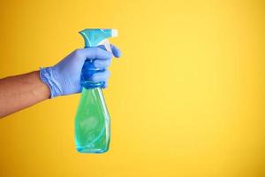 holding a plastic bottle spraying disinfect against yellow background photo