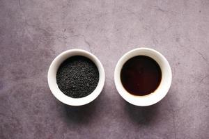 Black Cumin oils in a container on black background photo