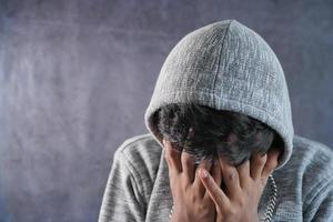 hombre triste en la cara de la cubierta de la capucha con las manos aisladas en negro. foto