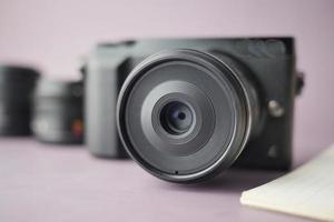 mirrorless camera, lens , notepad on table photo