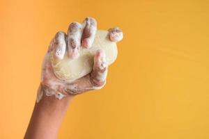 young man washing hands with soap on yellow background