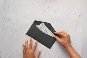 person hand putting cash in a envelope. photo