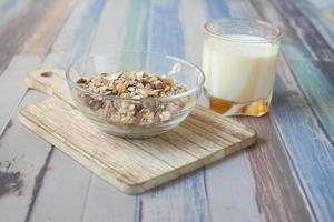 granola Musli in a bowl, and glass of milk on table photo