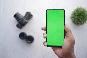 top view of holding smart phone with green screen and camera on background photo