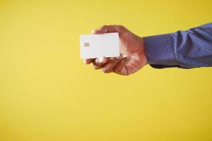 person hand holding credit card against yellow background photo