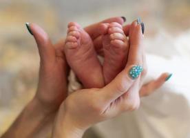 primer plano de las manos de la madre y los pies pequeños del bebé. foto