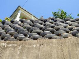 Wall of old tires. Unusual decoration of the land. Wheel fence.  Penetration protection. Flowerbeds photo