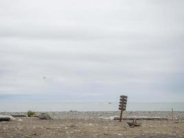 Wooden pointer on the beach. Mockup in nature. Recreation and tourism. photo