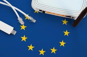 European union flag depicted on table with internet rj45 cable, wireless usb wifi adapter and router. Internet connection concept photo