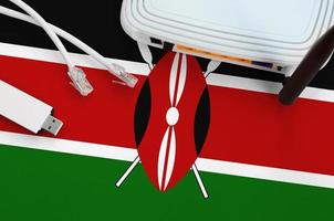 Kenya flag depicted on table with internet rj45 cable, wireless usb wifi adapter and router. Internet connection concept photo