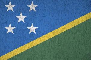 Solomon Islands flag depicted in bright paint colors on old relief plastering wall. Textured banner on rough background photo