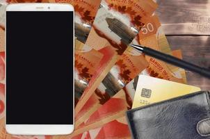 50 Canadian dollars bills and smartphone with purse and credit card. E-payments or e-commerce concept. Online shopping and business with portable devices photo