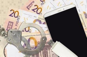 20 Belorussian rubles bills and smartphone with police handcuffs. Concept of hackers phishing attacks, illegal scam or malware soft distribution photo