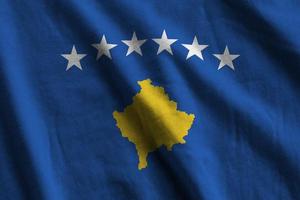 Kosovo flag with big folds waving close up under the studio light indoors. The official symbols and colors in banner photo