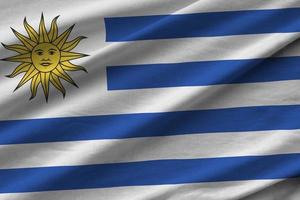 Uruguay flag with big folds waving close up under the studio light indoors. The official symbols and colors in banner photo