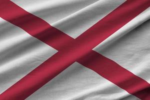 Alabama US state flag with big folds waving close up under the studio light indoors. The official symbols and colors in banner photo