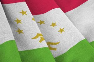 Tajikistan flag with big folds waving close up under the studio light indoors. The official symbols and colors in banner photo