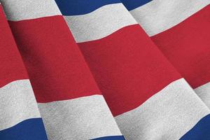 Costa Rica flag with big folds waving close up under the studio light indoors. The official symbols and colors in banner photo