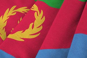 Eritrea flag with big folds waving close up under the studio light indoors. The official symbols and colors in banner photo