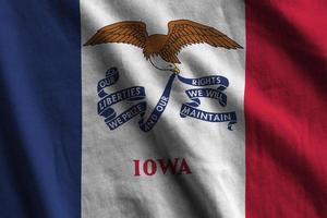 Iowa US state flag with big folds waving close up under the studio light indoors. The official symbols and colors in banner photo