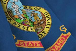 Idaho US state flag with big folds waving close up under the studio light indoors. The official symbols and colors in banner photo