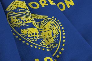 Oregon US state flag with big folds waving close up under the studio light indoors. The official symbols and colors in banner photo