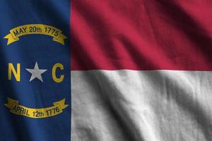 North Carolina US state flag with big folds waving close up under the studio light indoors. The official symbols and colors in banner photo