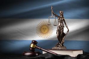 Argentina flag with statue of lady justice, constitution and judge hammer on black drapery. Concept of judgement and guilt photo